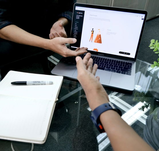 person using macbook pro on white table